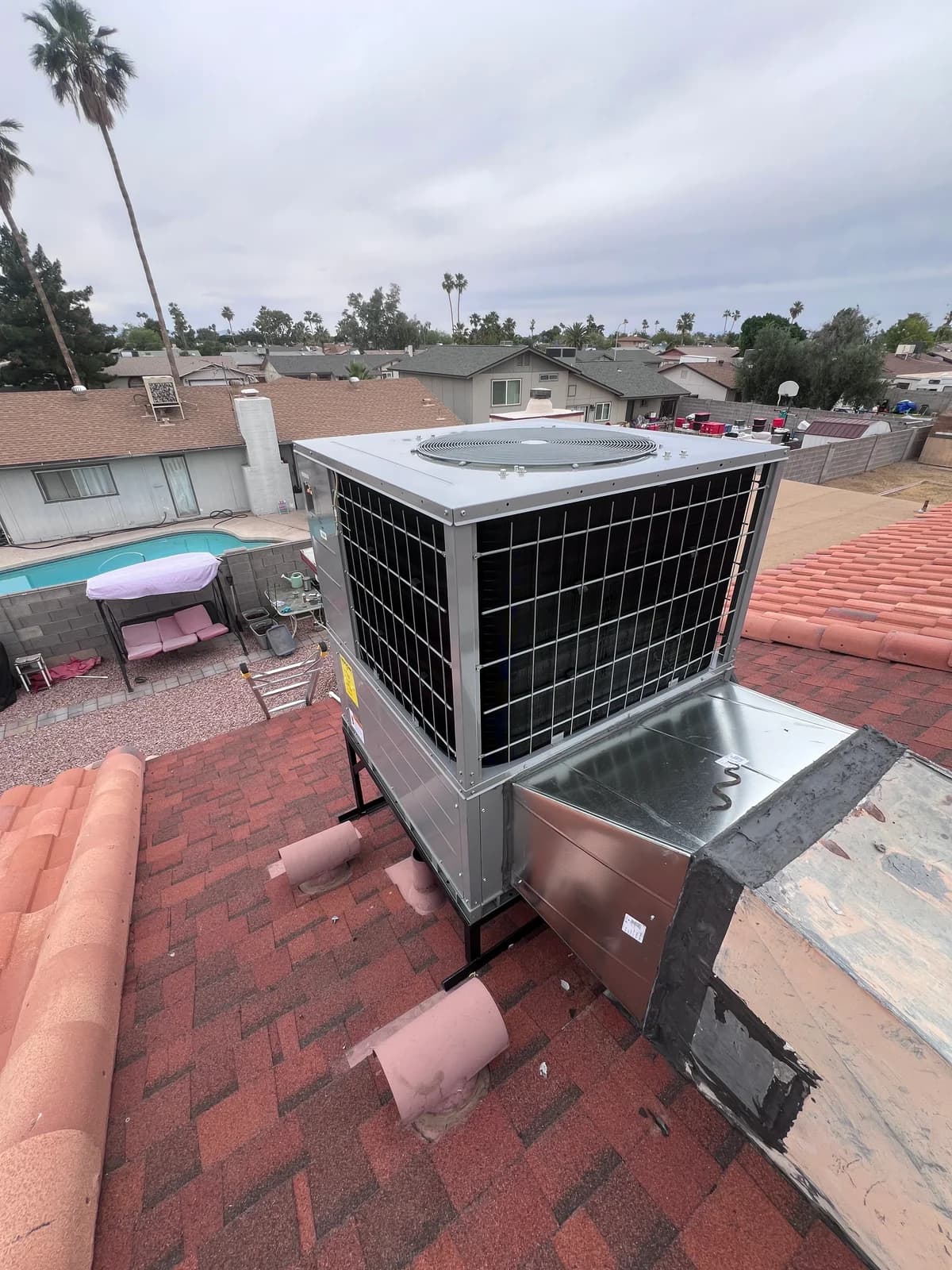 Wide rooftop view showing the packaged unit, duct transition, and completed work area