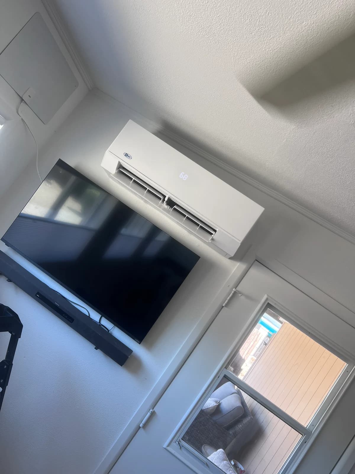 Finished wall-mounted mini split indoor unit installed above a television in an Arizona room