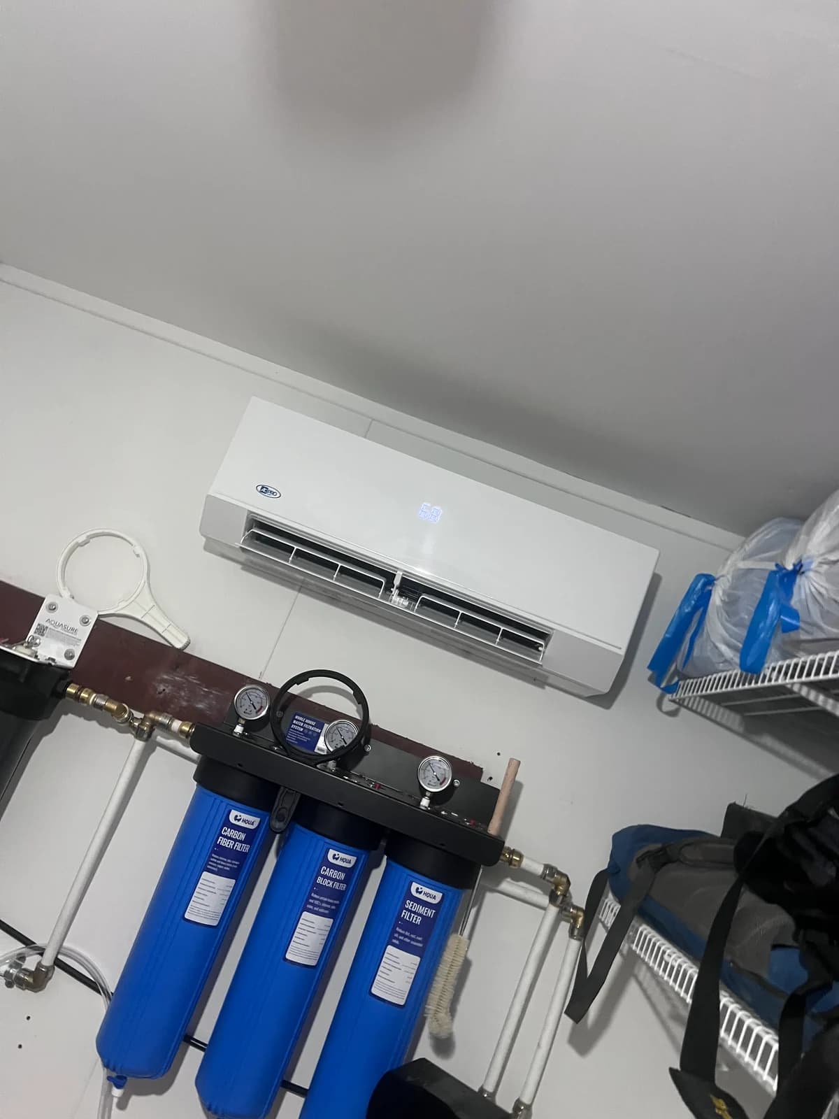 Wall-mounted mini split serving a garage utility area with organized filtration equipment below